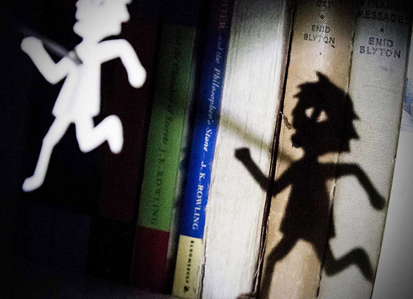 Image of a cut-out doll reflected on children's books